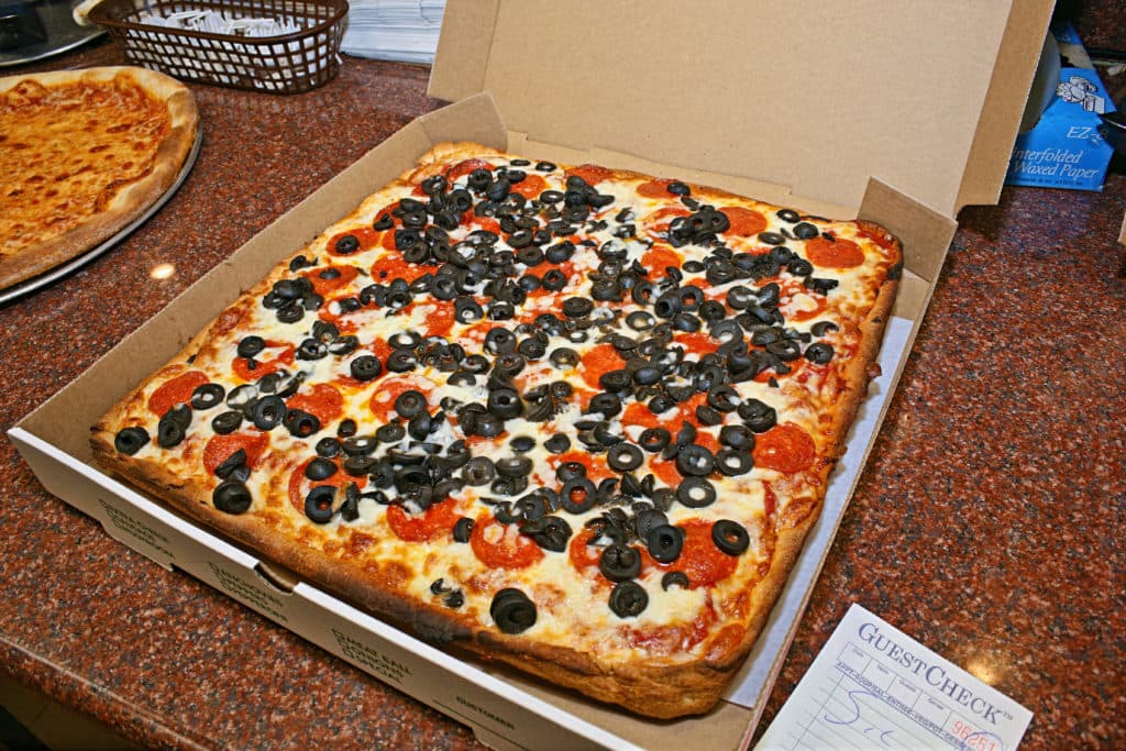 Fresh out of the oven Sicilian pizza with pepperoni and olives